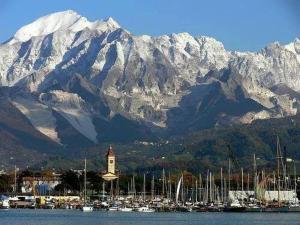 a group of boats in a harbor with a snow covered mountain at Mare e Monti Apartment in Marina di Carrara