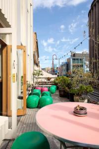un patio con una mesa rosa y sillas verdes en Alabama Hotel Hobart, en Hobart