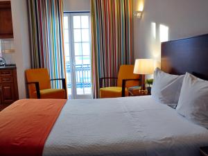 ein Hotelzimmer mit einem Bett und zwei Stühlen in der Unterkunft Patios Da Vila Boutique Apartments by AC Hospitality Management in Vila Nova de Milfontes