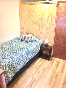 a bed in a room with a wooden wall at Departamento completo 40 mts2 - 2 habs y 1 futón - Centro Tomé - 5 personas max - Edificio Don Francisco in Tomé