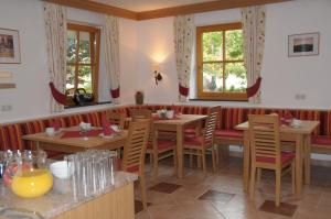 restauracja z drewnianymi stołami i krzesłami oraz oknami w obiekcie Haus Alpenflora w mieście Werfenweng