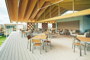 鶴岡市にあるショウナイホテル スイデンテラス の木製のテーブルと椅子、デッキが備わるレストラン