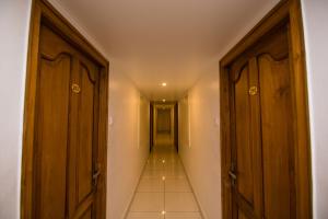 a hallway with two wooden doors and a long corridor at Hotel Kapilavasthu in Palakkad