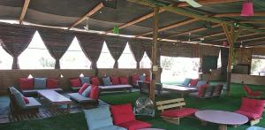 einen Pavillon mit roten und blauen Stühlen und Tischen in der Unterkunft Ras Hasita in H̱aẕeva
