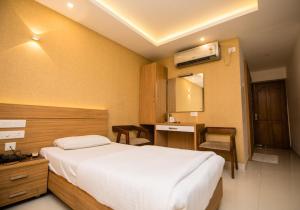 a hotel room with a bed and a desk and a mirror at Hotel Kapilavasthu in Palakkad