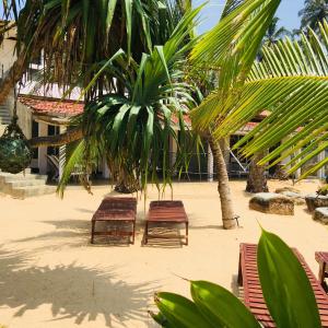 4 sillas y una palmera en una playa en Villa Thotupola en Ahungalla