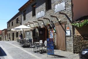 ceglany budynek ze stołami, krzesłami i parasolem w obiekcie Casa Rural Monfragüe w mieście Villarreal de San Carlos