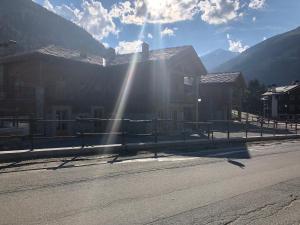 a building with the sun shining on the side of the road at Monolocale Belvedere vda La Thuile CIR 0067 in La Thuile
