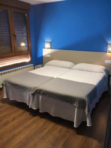 1 dormitorio con 2 camas y pared azul en Narcea Turismo Real, en Cangas del Narcea