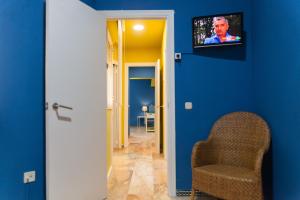 een hal met een stoel en een tv aan een blauwe muur bij Ritual Sevilla Suite Alameda 5 in Sevilla