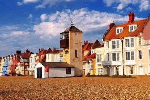 a group of buildings and a lighthouse on a beach at The Boat House in Aldeburgh