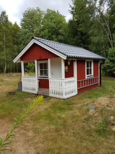 a red and white shed with a porch at Rinkaby Stugområde 31 in Tävelsås