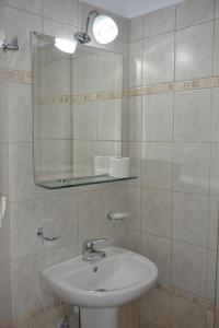 a white bathroom with a sink and a mirror at Iliaktida Studios in Vasiliki