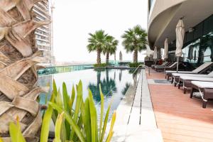 uma piscina do hotel com espreguiçadeiras e palmeiras em DAMAC Upper Crest in Downtown em Dubai