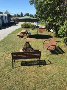 two benches and a picnic table with an umbrella at Motel de L'Anse et Camping Rimouski in Rimouski