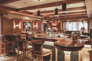 a bar in a restaurant with wooden walls and wooden stools at Alpenresort Fluchthorn in Galtür