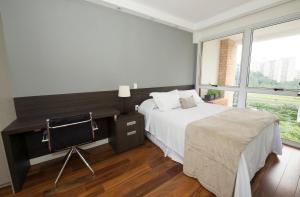 1 dormitorio con cama, escritorio y ventana en Berrini, en São Paulo
