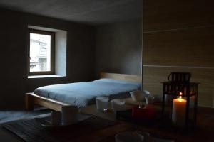Un dormitorio con una cama y una mesa con una vela en B&B éve en Aosta
