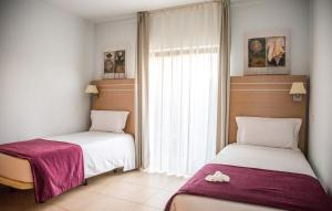 two beds sitting in a room with a window at Sagres Time Apartamentos in Sagres +29 photos