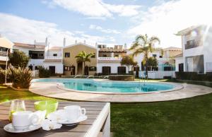 a table with cups and saucers next to a pool at Sagres Time Apartamentos in Sagres