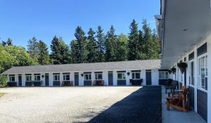 a large white building with trees in the background at Motel de L'Anse et Camping Rimouski in Rimouski