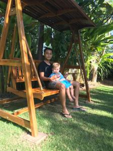 
a man and a child sitting on a bench at El Homestay Bali in Nusa Dua
