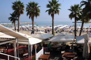 a beach with palm trees and tables and umbrellas at La casa di Luna in San Benedetto del Tronto
