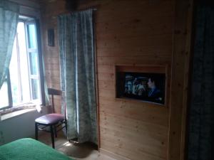 a bedroom with a tv in a wooden wall at Il Càssero in Pomaretto