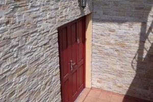 a red door on a brick building with a brick wall at Apartment v historickom centre in Bardejov +5 photos