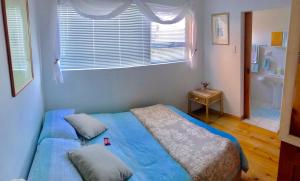 a bedroom with a bed with blue sheets and a window at Casa Oma in Fisherhaven