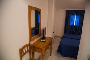 a small room with a bed and a table with a mirror at Hostal Acuario in Gálvez