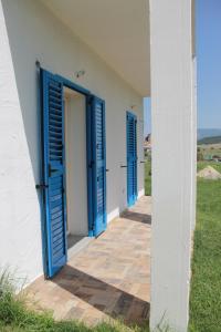 una fila di porte blu su un edificio bianco di S'Olivariu Village Affittacamere a Piscinas