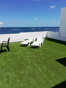 オルソラにあるOcean Sunshineの海辺の芝生に座る白い椅子