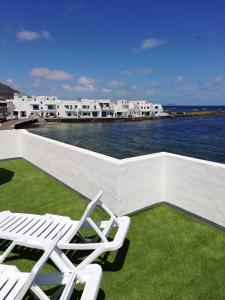 two white chairs sitting on top of a balcony with the water at Ocean Sunshine in Orzola