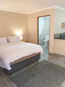 een slaapkamer met een groot bed en een badkamer bij 298 on 34th in Pretoria