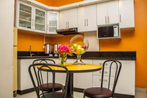 una cocina con una mesa amarilla con sillas y un jarrón de fruta en Hotel Margarita 2, en Quito