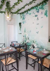une salle à manger avec des tables, des chaises et des plantes sur le mur dans l'établissement b&b Napoli Capitale, à Naples