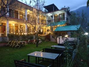 a building with lights on it with tables and chairs at Madpackers Manali in Manāli