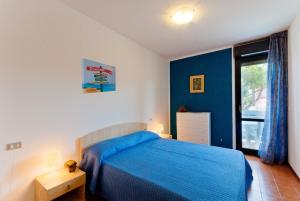 a bedroom with a blue bed and a window at Quadrangolo in Bibione