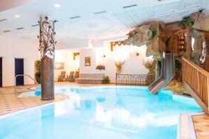 a pool in a hotel with a water slide at Hotel Alpe in Canazei