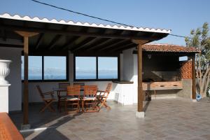 eine Terrasse mit Stühlen, einem Tisch und einem Grill in der Unterkunft Casa El Molino in Puntallana