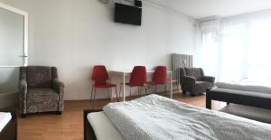 a room with a bed and chairs and a television at Szelestey utcai apartman (Szombathely) in Szombathely