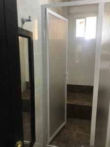 baño con puerta de ducha y espejo en Santa Marta Apartamentos Salazar - Maria Paula, en Santa Marta