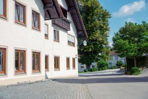 eine Kopfsteinpflasterstraße neben einem weißen Gebäude in der Unterkunft Gasthaus und Pension Zur Linde in Rot an der Rot