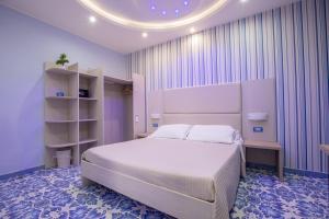 una camera da letto con un grande letto bianco e pareti viola di B&b Palazzo Aranci a Sorrento