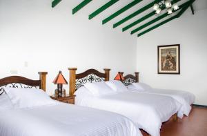 2 camas en una habitación blanca con sábanas blancas en Finca Hotel Valparaíso en Armenia