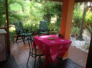 a table and chairs on a porch with a pink table cloth at Villa Manguier in Rivière-Salée