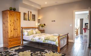 a bedroom with a bed and a wooden cabinet at Cyrus House in Dartford