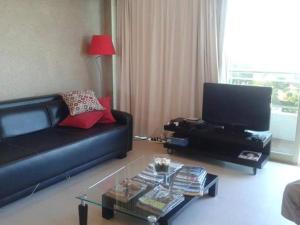 sala de estar con sofá negro y TV en Building Albar en Pinamar