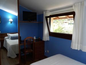 1 dormitorio con paredes azules, ventana y cama en Pensión Toranda, en Niembro